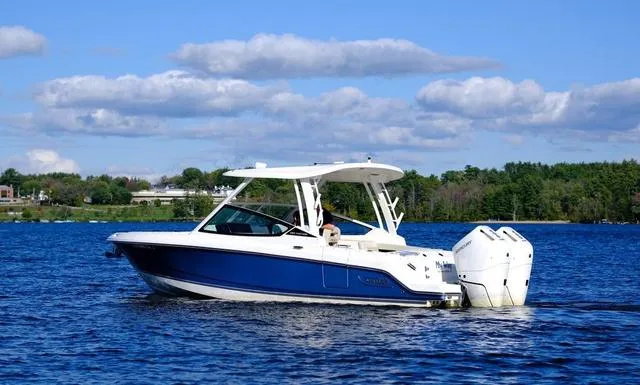 Slide: The Image of 2024 Boston Whaler 280 Vantage boat cruising on a serene lake under a clear blue sky. - 4