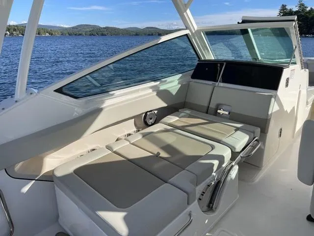 Slide: The Image of 2024 Boston Whaler 280 Vantage boat interior with cushioned seating by a lake. - 41