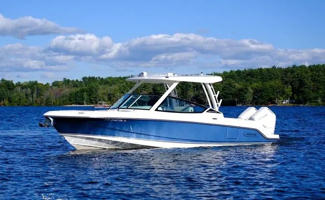 Slide: The Image of 2024 Boston Whaler 280 Vantage boat cruising on a serene lake under a clear blue sky. - 45