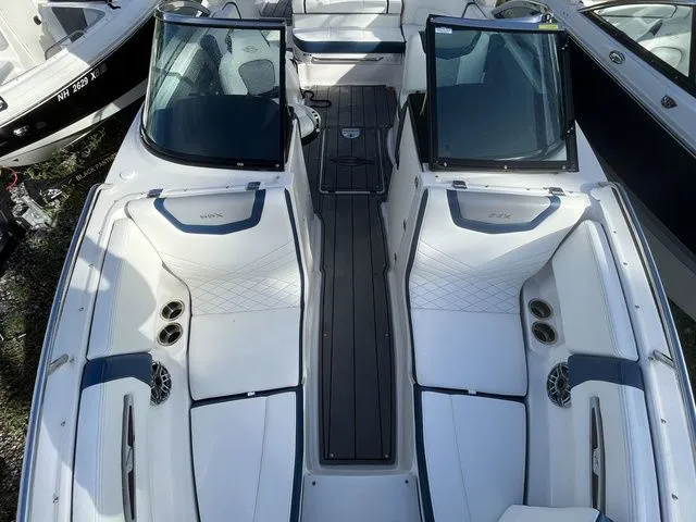 Slide: The Image of 2023 Chaparral 247 SSX boat interior with white and blue seating, open windshield, and cup holders. - 10