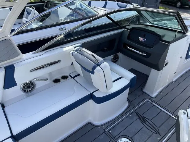 Slide: The Image of 2023 Chaparral 247 SSX boat interior with white and blue seating, modern dashboard, and cup holders. - 24