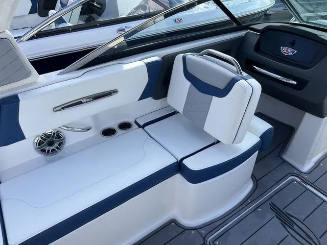 Slide: The Image of 2023 Chaparral 247 SSX boat interior with white and blue seating, cup holders, and speaker. - 25