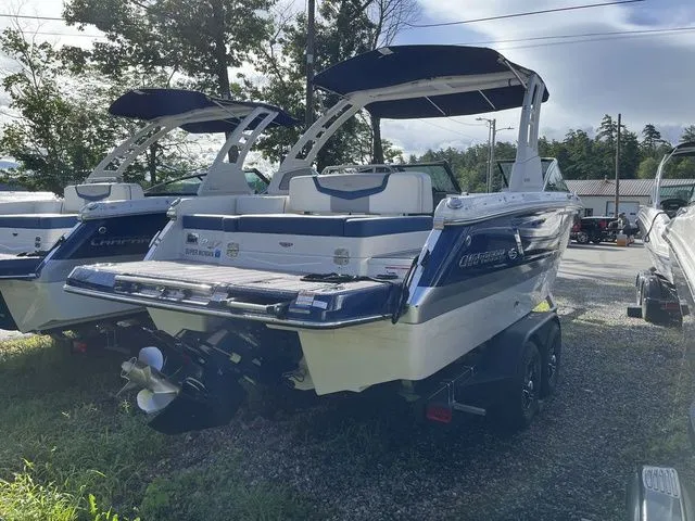 Slide: The Image of 2023 Chaparral 247 SSX boat, blue and white, parked on a trailer in a lot. - 3
