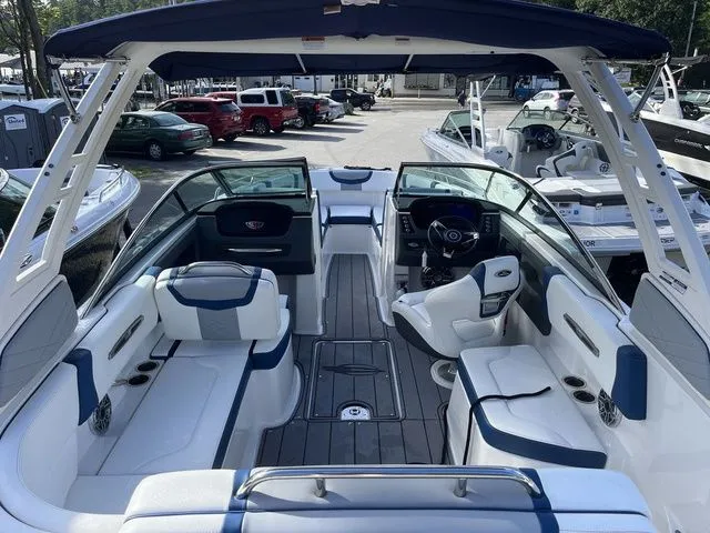Slide: The Image of 2023 Chaparral 247 SSX boat interior with white and blue seating, docked in a marina. - 5