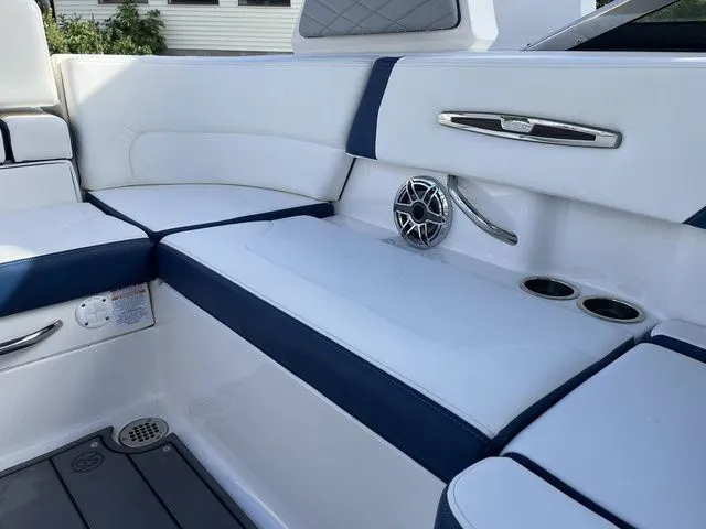 Slide: The Image of 2023 Chaparral 247 SSX boat interior with white and blue seating, speaker, and cup holders. - 6