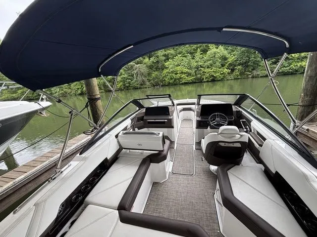 Slide: The Image of 2024 Cobalt R4 boat interior with sleek seating and canopy, docked by a lush riverside. - 5