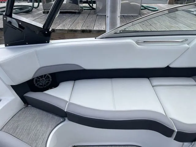 Slide: The Image of 2024 Cobalt 220S boat interior with white and gray seating, docked at a wooden pier. - 11