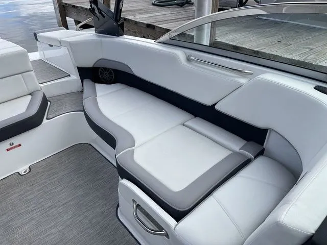 Slide: The Image of 2024 Cobalt 220S boat interior with white and gray seating, dockside view. - 17