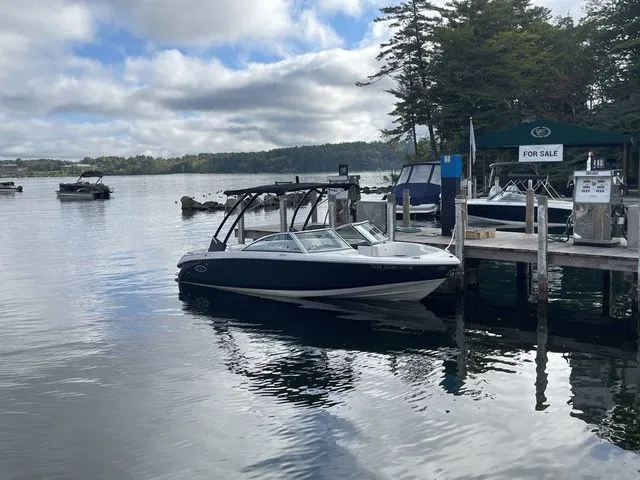 Slide: The Image of 2024 Cobalt 220S boat docked by a lakeside marina, under a cloudy sky. - 3