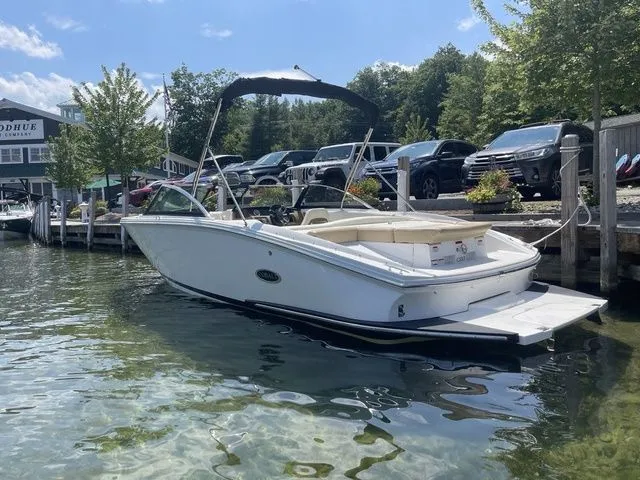 Slide: The Image of 2022 Cobalt CS23 boat docked on clear water, sunny day, trees and cars in background. - 1