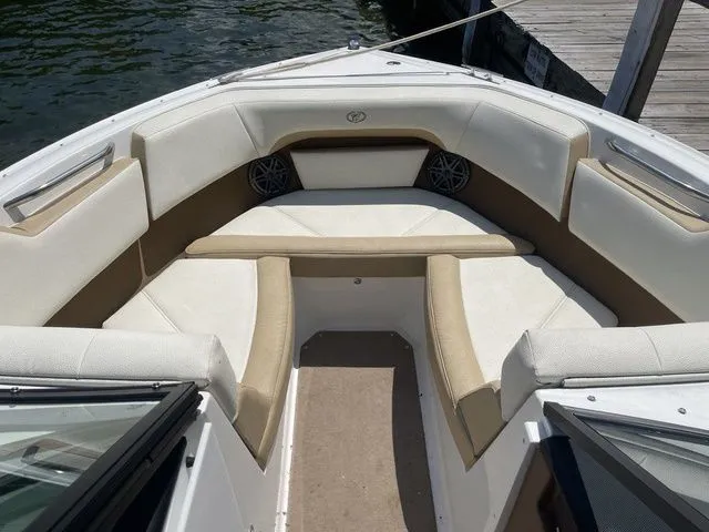 Slide: The Image of 2022 Cobalt CS23 boat interior with beige and white seating, docked by the water. - 12
