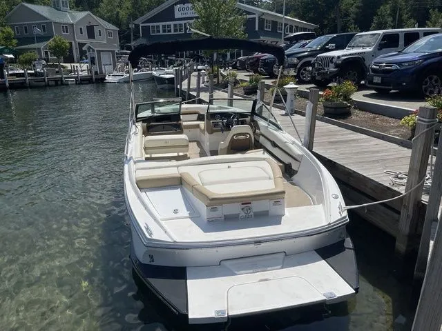 Slide: The Image of 2022 Cobalt CS23 boat docked at a marina with clear water and parked cars nearby. - 3
