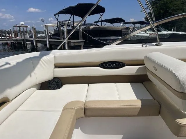 Slide: The Image of 2022 Cobalt CS23 boat interior with beige seating at a marina. - 7