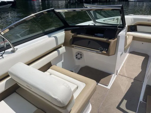 Slide: The Image of 2022 Cobalt CS23 boat interior with beige and white seating, docked by the water. - 8