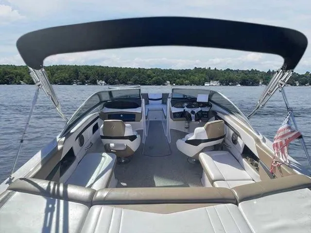 Slide: The Image of 2015 Four Winns H230 boat interior with seating, on a lake with forested shoreline. - 16