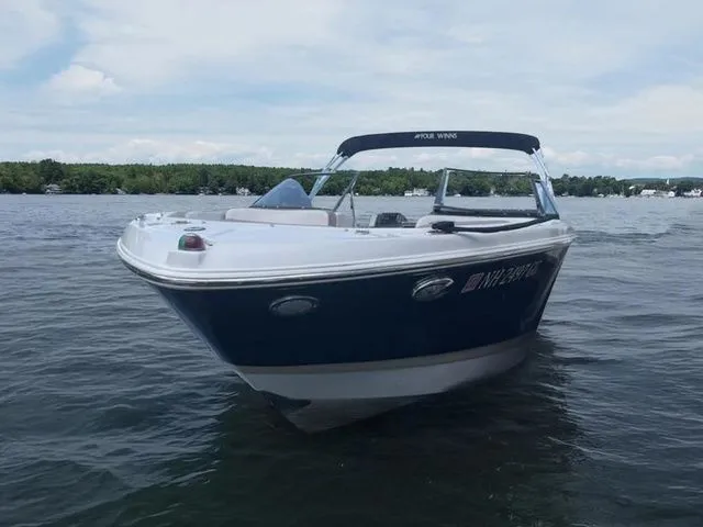 Slide: The Image of 2015 Four Winns H230 boat on a lake, featuring sleek design and blue exterior. - 2