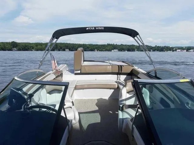 Slide: The Image of 2015 Four Winns H230 boat on a lake, featuring open seating and a canopy. - 7