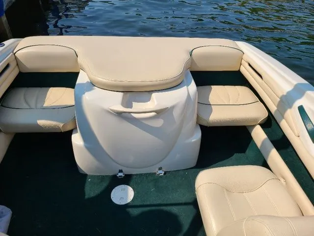 Slide: The Image of 2000 Sea Ray 185BR boat interior with beige seating and green carpet, near water. - 12