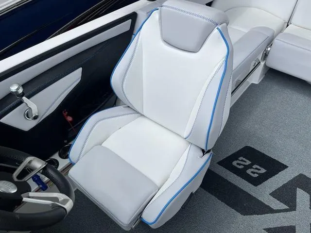 Slide: The Image of 2021 MasterCraft XT22 boat interior with sleek white and gray seating, blue accents. - 16