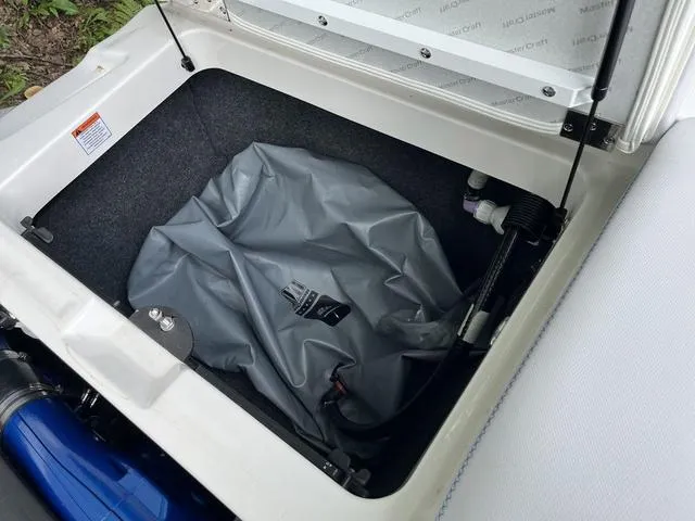 Slide: The Image of 2021 MasterCraft XT22 storage compartment with gray cover and visible components. - 23