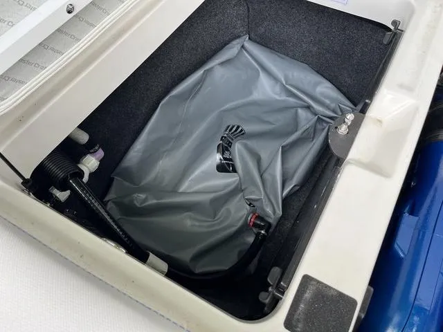 Slide: The Image of 2021 MasterCraft XT22 storage compartment with gray cover and visible fittings. - 24