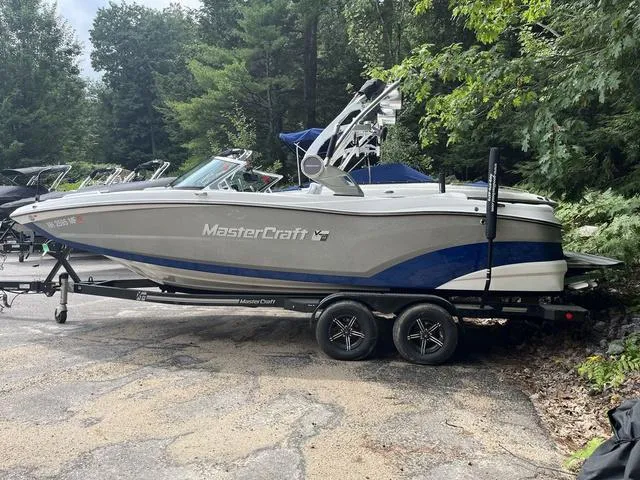Slide: The Image of 2021 MasterCraft XT22 boat on trailer, parked near trees. - 3