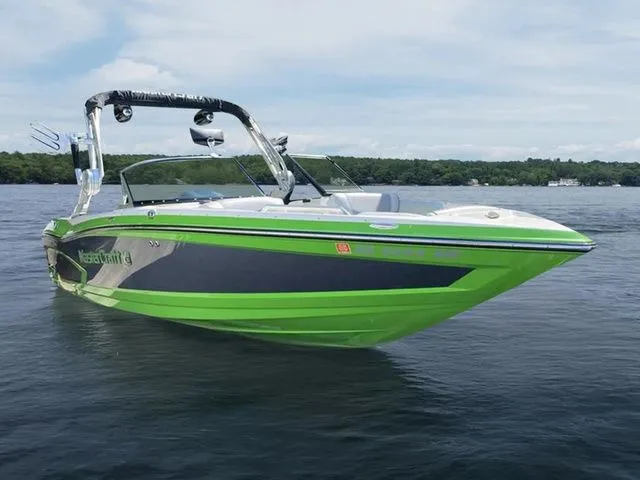 Slide: The Image of 2014 MasterCraft X30 boat with vibrant green and black design on a calm lake. - 1
