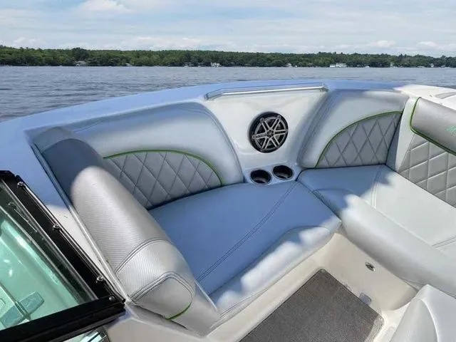 Slide: The Image of 2014 MasterCraft X30 boat interior with gray seating and speaker, on a calm lake. - 12
