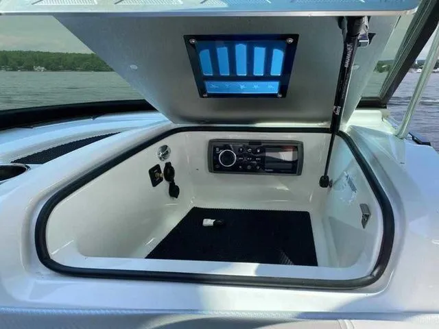 Slide: The Image of 2014 MasterCraft X30 boat storage compartment with control panel, open on a lake. - 16
