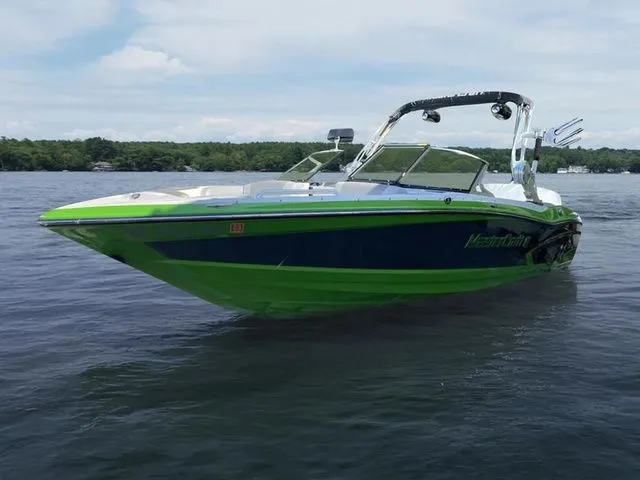 Slide: The Image of 2014 MasterCraft X30 boat on calm lake with green and blue design. - 2