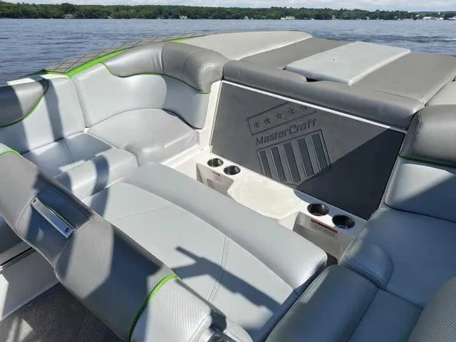 Slide: The Image of 2014 MasterCraft X30 boat interior with gray seating and cup holders on a lake. - 21