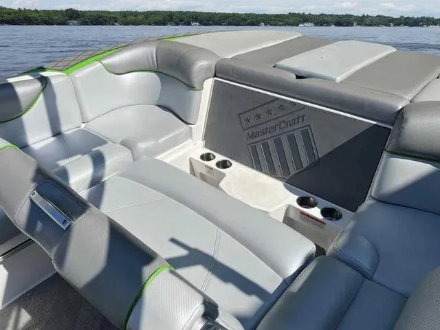 Slide: The Image of 2014 MasterCraft X30 boat interior with gray seating and cup holders on a lake. - 22