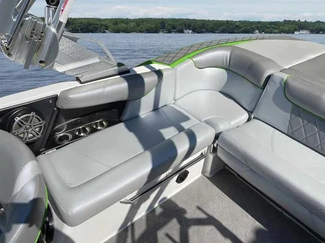 Slide: The Image of 2014 MasterCraft X30 boat interior with gray seating and cup holders on a lake. - 23