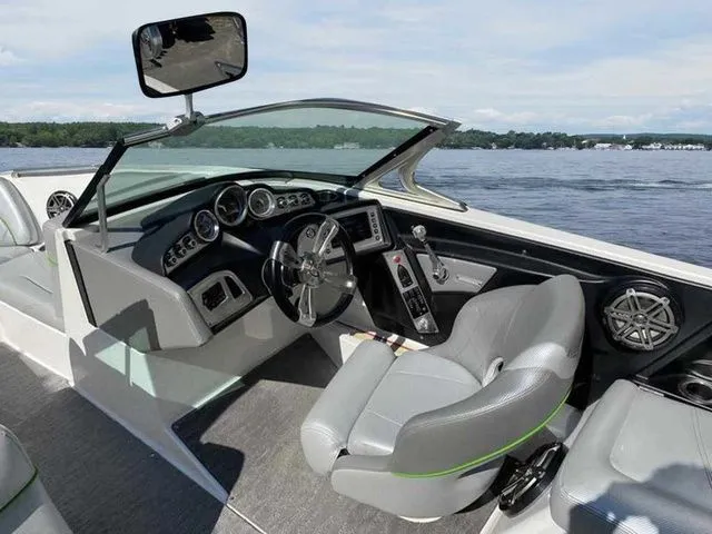Slide: The Image of 2014 MasterCraft X30 boat interior with sleek dashboard and comfortable seating on a lake. - 24