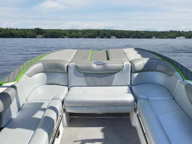 Slide: The Image of 2014 MasterCraft X30 boat interior with gray seating, on a lake with forested shoreline. - 27