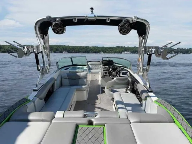 Slide: The Image of 2014 MasterCraft X30 boat interior with seating, speakers, and steering, on a calm lake. - 36