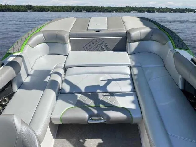 Slide: The Image of 2014 MasterCraft X30 boat interior with gray seating and green accents on a lake. - 37