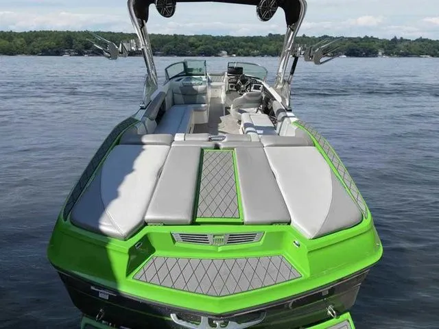 Slide: The Image of 2014 MasterCraft X30 boat with green and gray seating on a calm lake. - 6