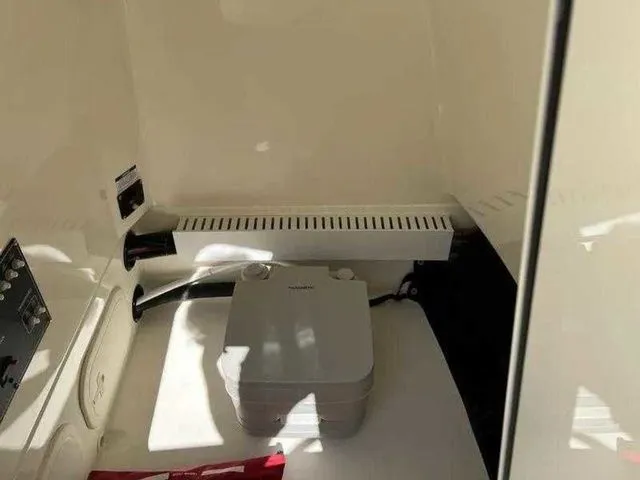 Slide: The Image of 2024 Boston Whaler 230 Outrage interior with compact marine toilet and storage area. - 13