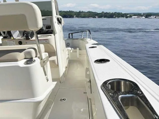 Slide: The Image of 2024 Boston Whaler 230 Outrage boat interior with cup holders, on a calm lake. - 17
