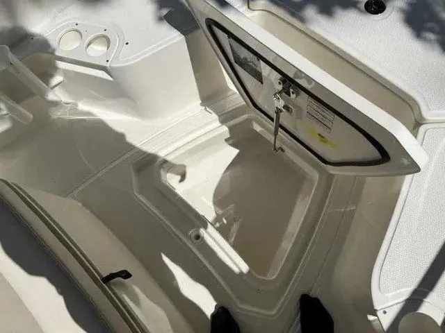 Slide: The Image of 2024 Boston Whaler 230 Outrage boat storage compartment with open hatch and cup holders. - 5