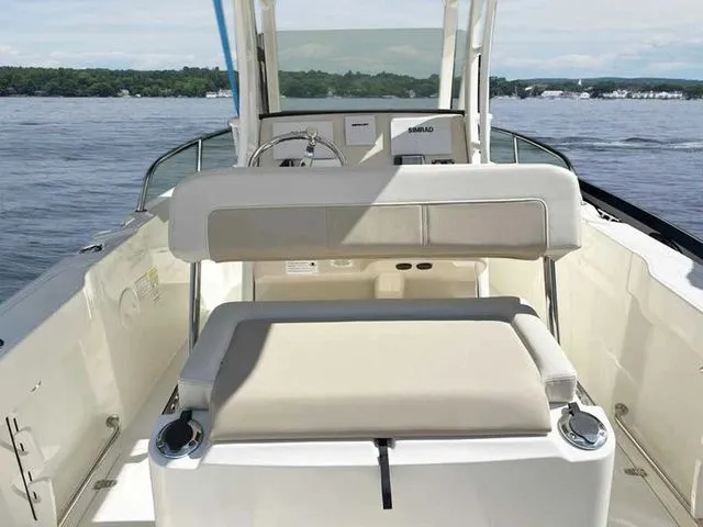 Slide: The Image of 2024 Boston Whaler 230 Outrage boat interior with seating and steering console on a calm lake. - 6