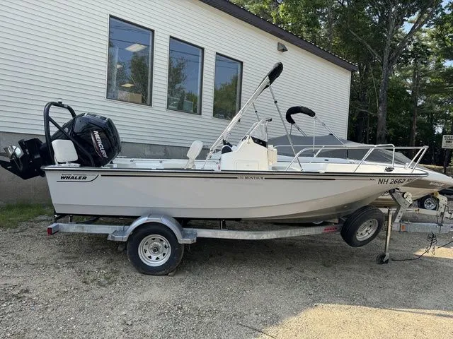 Slide: The Image of 2025 Boston Whaler 170 Montauk boat on trailer, parked outdoors near a building. - 1
