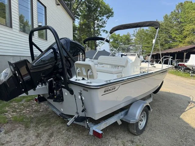 Slide: The Image of 2025 Boston Whaler 170 Montauk boat on trailer, parked outdoors near a house. - 2