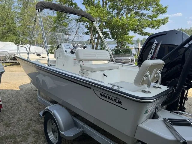 Slide: The Image of 2025 Boston Whaler 170 Montauk boat on trailer, parked outdoors near trees. - 5