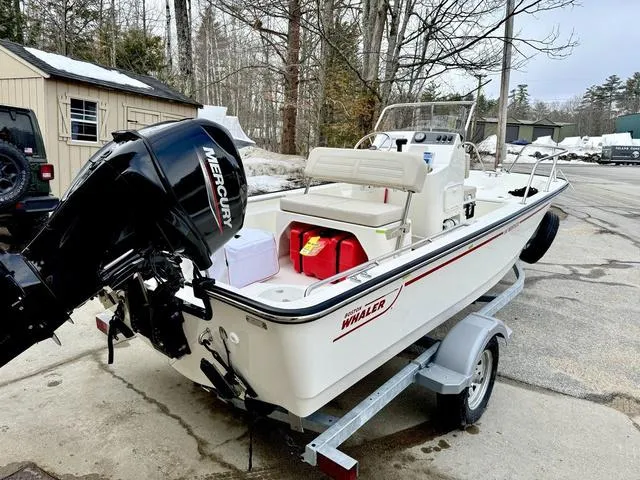 Slide: The Image of 2025 Boston Whaler 150 Montauk boat on trailer with Mercury engine, parked outdoors. - 3