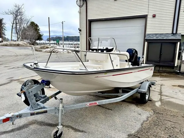 Slide: The Image of 2025 Boston Whaler 150 Montauk boat on trailer, parked outside a garage. - 6