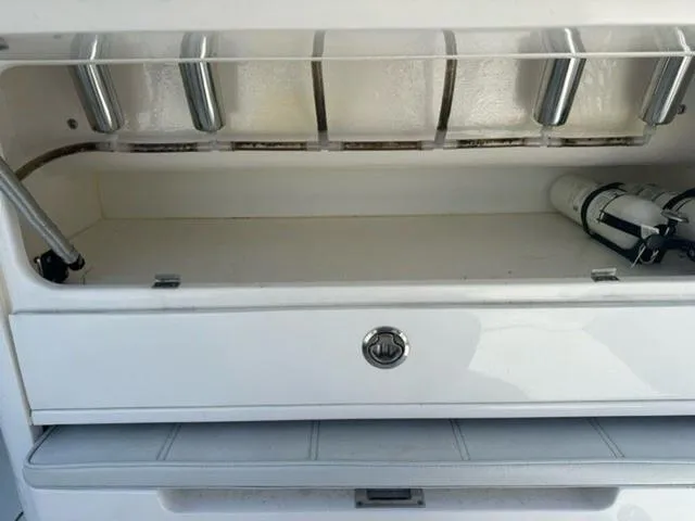 Slide: The Image of 2019 Contender 32ST boat storage compartment with rod holders and fire extinguisher. - 15