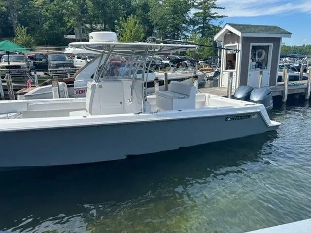 Slide: The Image of 2019 Contender 32ST boat docked at marina with clear water and lush greenery. - 19