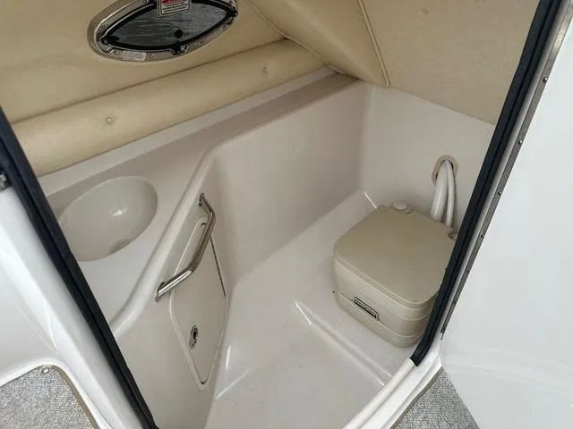 Slide: The Image of 2005 Sea Ray 240 Sundeck interior with compact marine toilet and sink. - 19